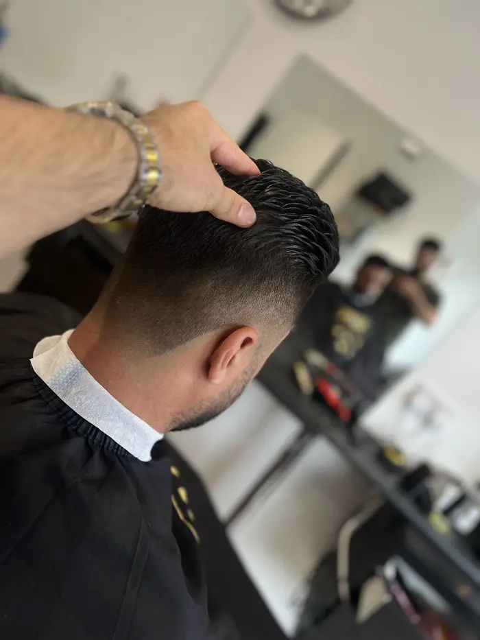 Barber styling a textured crop with mid fade