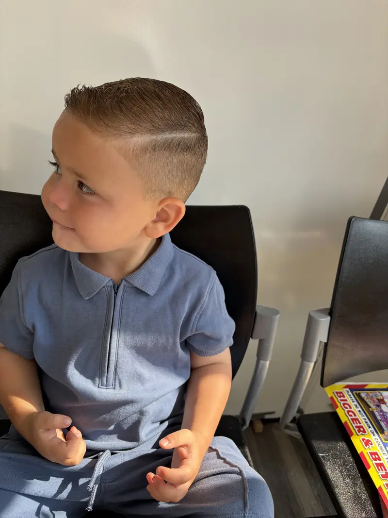 Young boy smiling in the waiting seat after his haircut at King barber